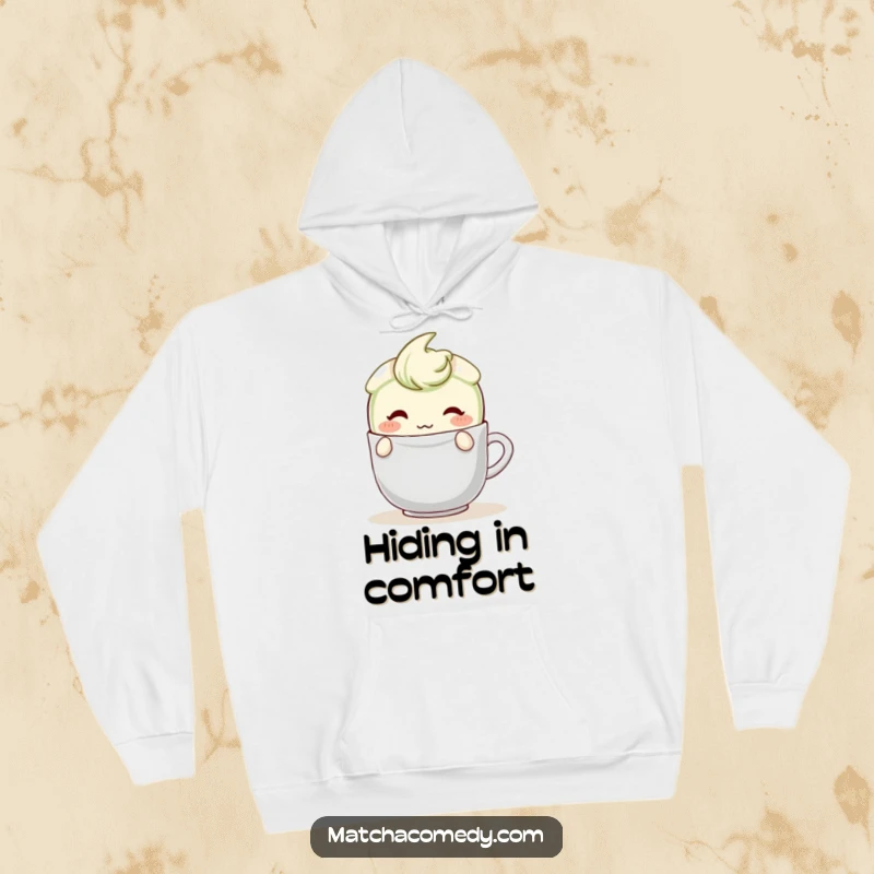 Funny Matcha Latte Hoodie featuring a blushing character peeking shyly from behind a teabag, offering a warm and endearing feel.